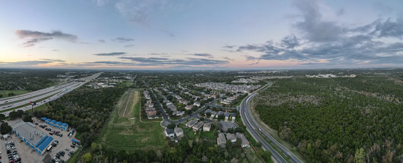 Aerial view of Central Texas neighborhood at sunset with Austin skyline in the distance